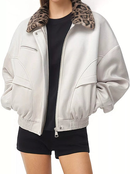 A person wearing an oversized light beige faux-leather jacket with a brown and black leopard-print faux-fur collar, styled over a black t-shirt and black shorts.