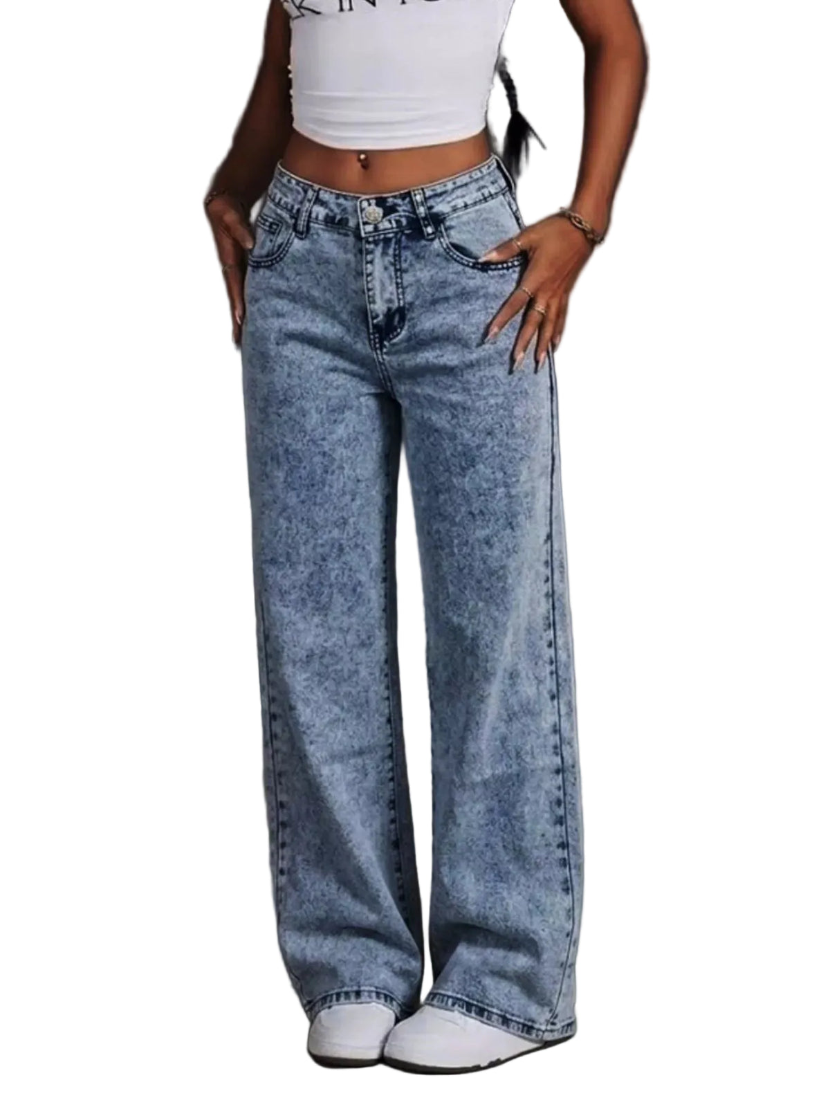 A person wearing light-wash blue wide-leg jeans with a faded mineral wash effect, paired with a white crop top and white sneakers, standing in an industrial-style concrete setting.