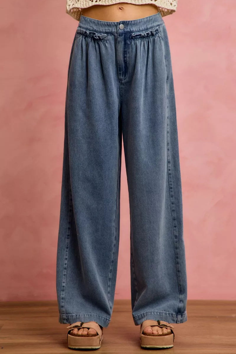 Blue jeans worn by a person on a pink background