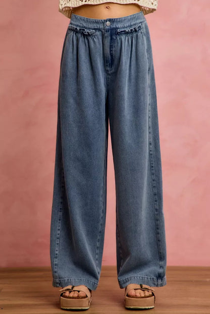 Blue jeans worn by a person on a pink background