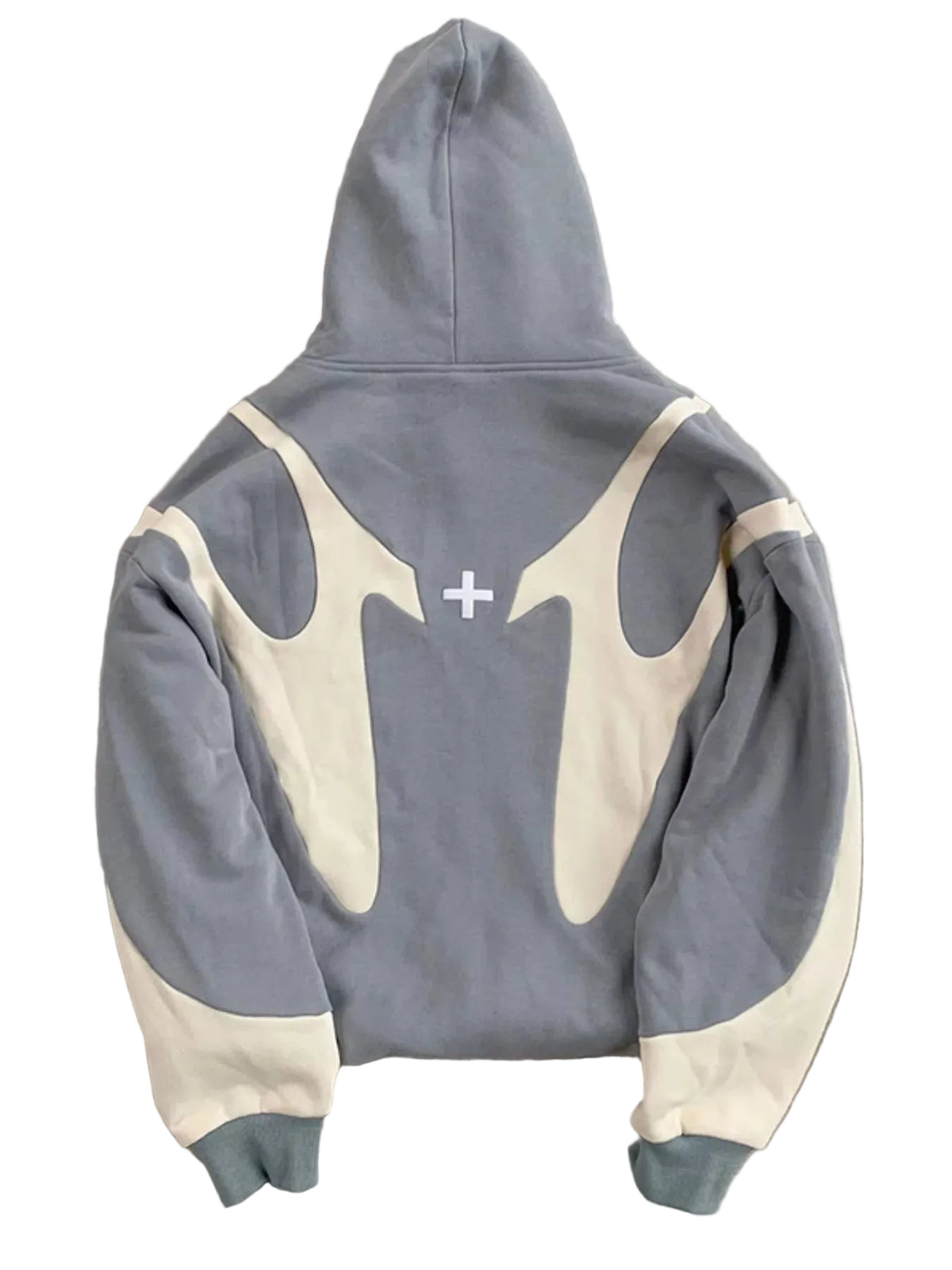 A gray and cream color-blocked hoodie laid flat on a textured gray concrete surface, showing the back view with a small white cross graphic in the center.