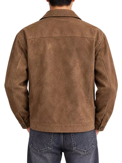 A man viewed from the back wearing a brown suede or faux-suede jacket and dark blue jeans against a plain light gray studio background.
