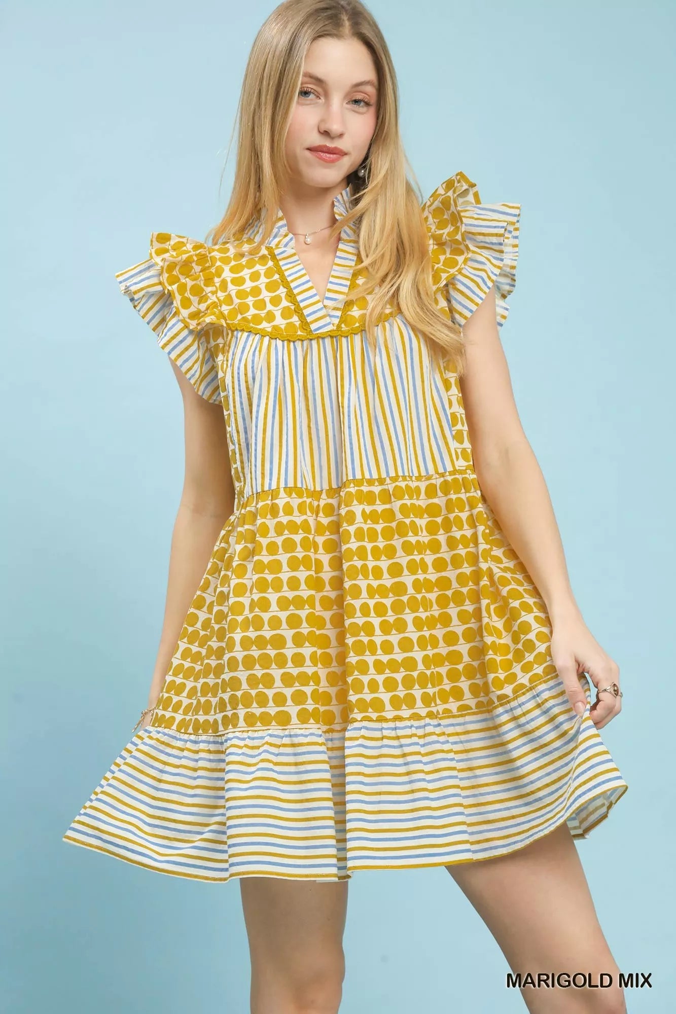 Woman wearing a yellow and white patterned dress on a light blue background