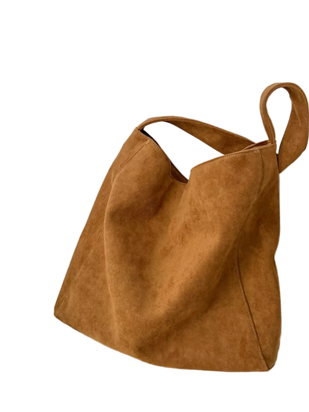 A large slouchy suede tote bag in a warm camel brown color, resting on a white surface next to a small ceramic cup and saucer against a white wall.