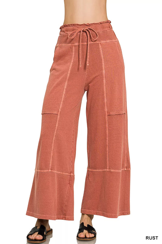 Rust-colored wide-leg pants with a drawstring waist on a white background.