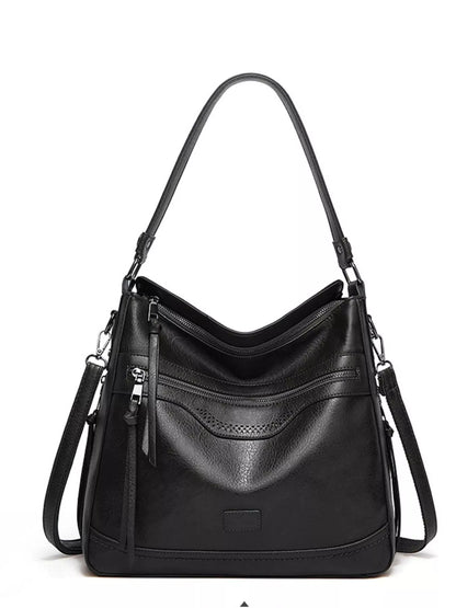A black pebbled leather hobo shoulder bag with a top handle, a front zippered pocket, and a detachable shoulder strap, shown against a plain white background.