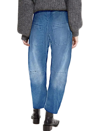 Rear view of a person wearing blue denim jeans with a relaxed straight-leg fit, paired with a gray ribbed sweater and black ankle boots, against a plain light background.
