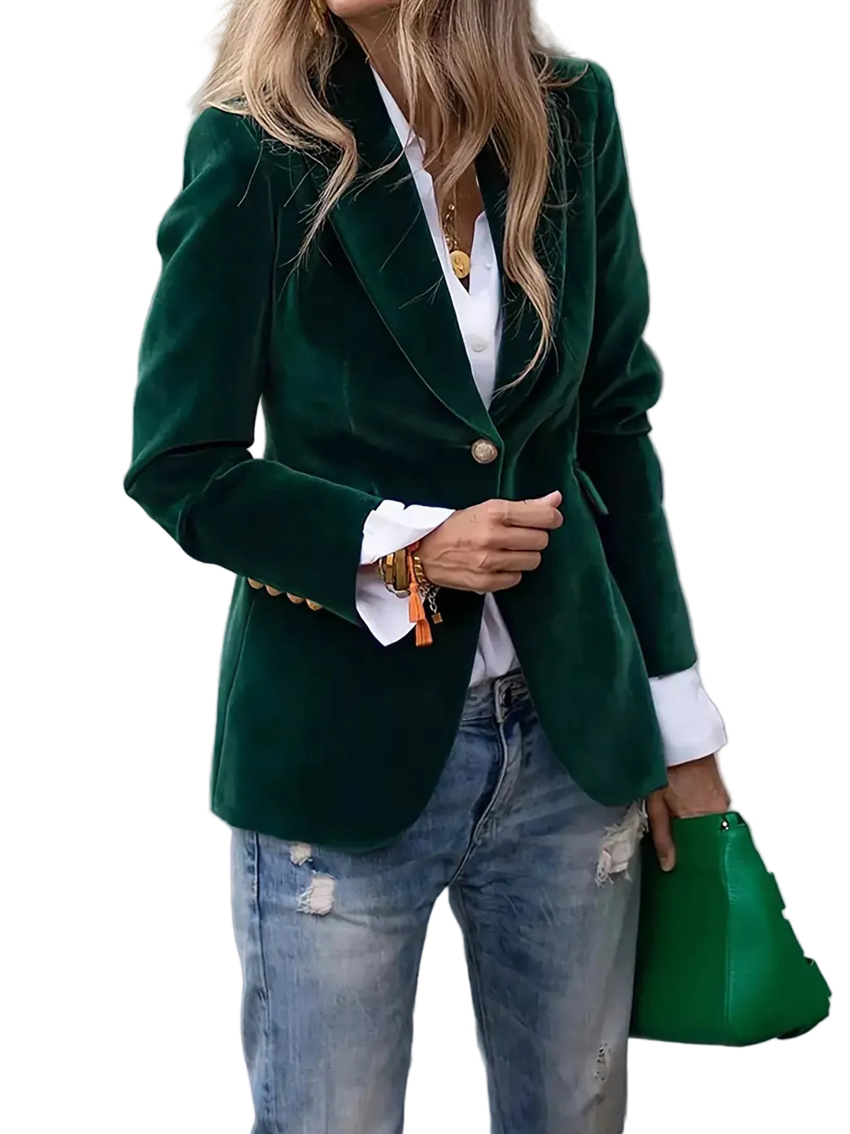 A woman wearing a dark green velvet blazer over a white collared shirt and light-wash distressed jeans, holding a green handbag in an outdoor urban setting.