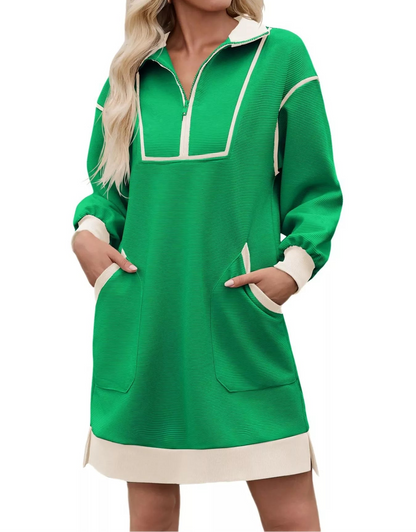 A woman wearing a bright green long-sleeve pullover dress with cream-colored trim, a half-zip neckline, and front patch pockets, shown against a plain white background.