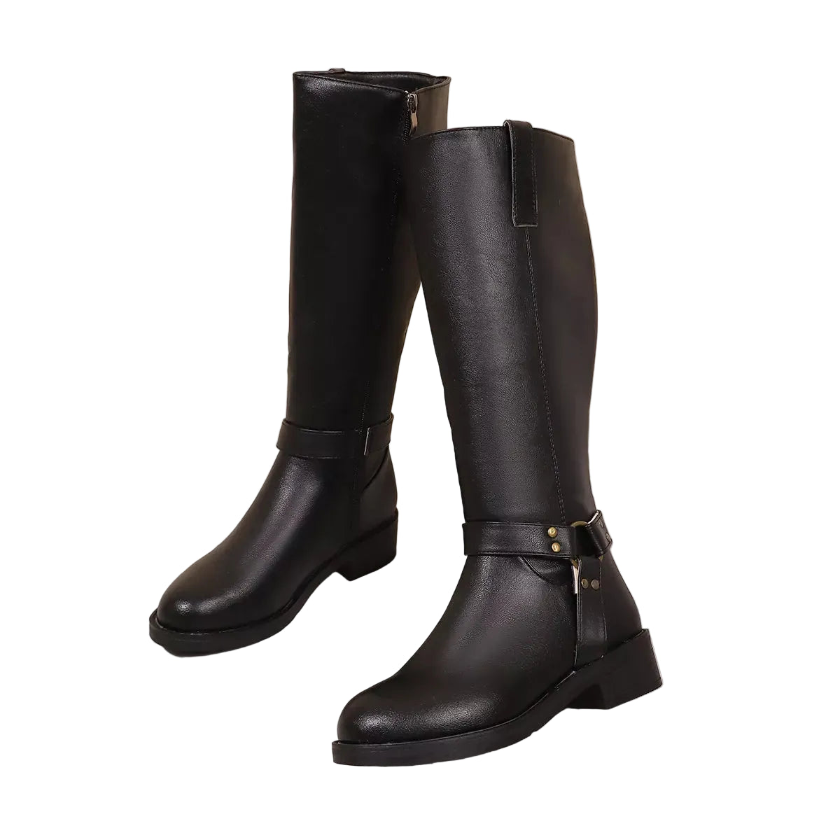 A pair of black knee-high leather boots with low block heels and buckle strap details, displayed on a marble-patterned surface against a beige wall.