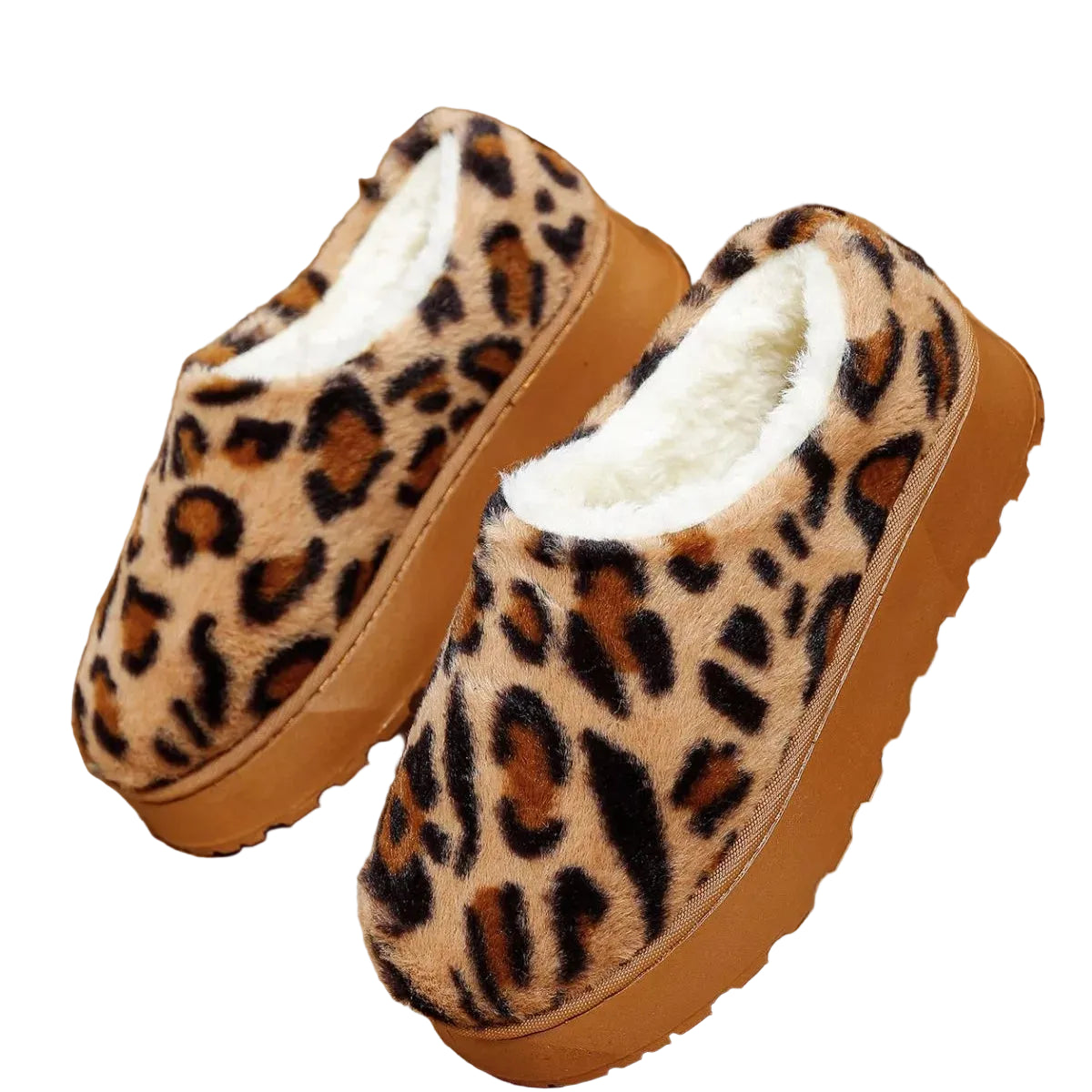 A pair of plush slip-on mule slippers with a leopard print pattern, featuring a warm tan base, dark brown and black spots, and a thick tan sole, lined with soft white faux fur. They are displayed on a tiled floor next to a wooden lattice screen.