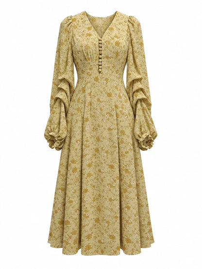 A long-sleeved midi dress with a ruffled yoke, buttoned front, and voluminous tiered sleeves, featuring a yellow and brown floral pattern, shown on a plain white background.