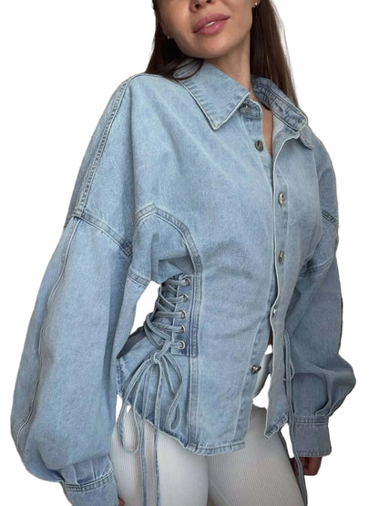 Person wearing a light blue denim jacket with lace-up front in an indoor setting.