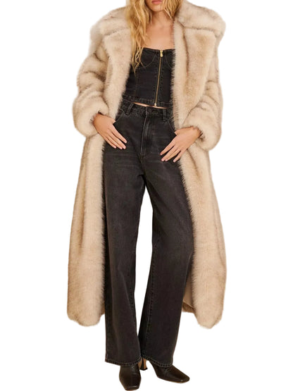 A model wearing a long, fluffy beige faux-fur coat over a black cropped top and black wide-leg jeans, standing against a plain off-white wall.