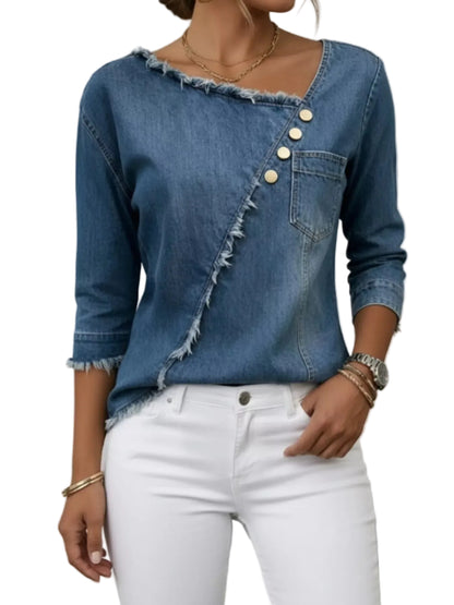 A woman wearing a blue denim top with an asymmetrical button closure, frayed edges, and a chest pocket, paired with white pants.