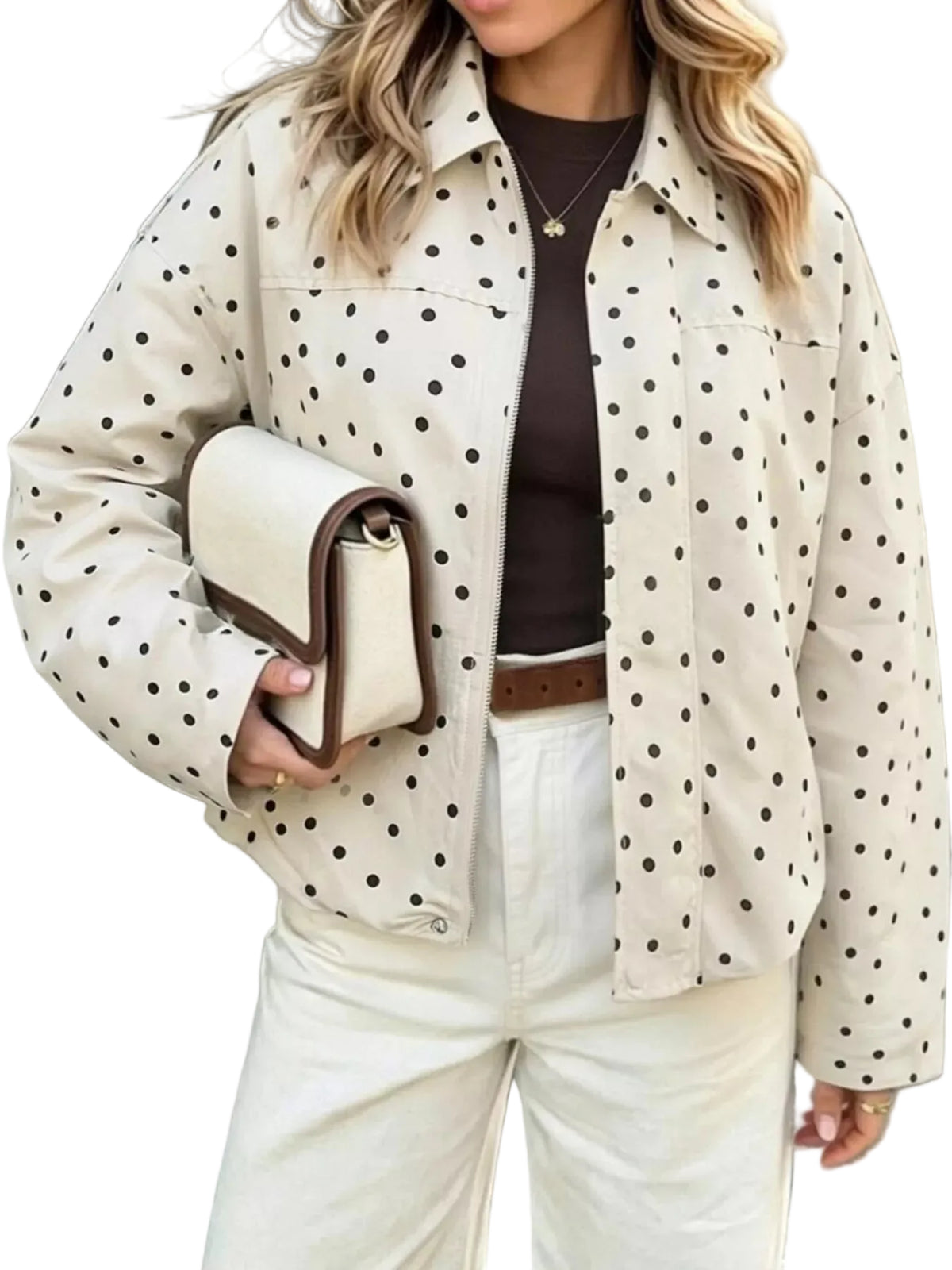 A woman wearing a cream-colored jacket with black polka dots, styled with white pants, a dark brown top, and holding a matching cream clutch bag.