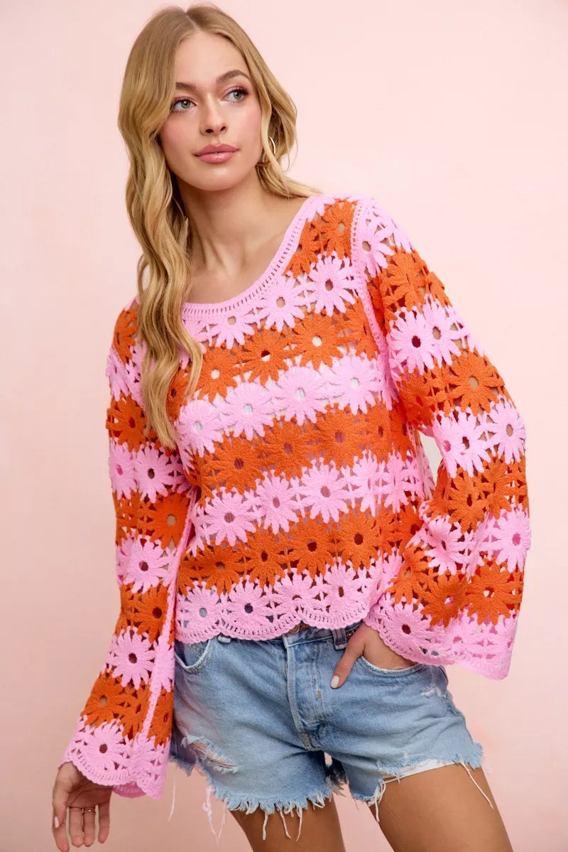 Woman wearing a colorful crochet sweater with pink and orange flowers on a beige background