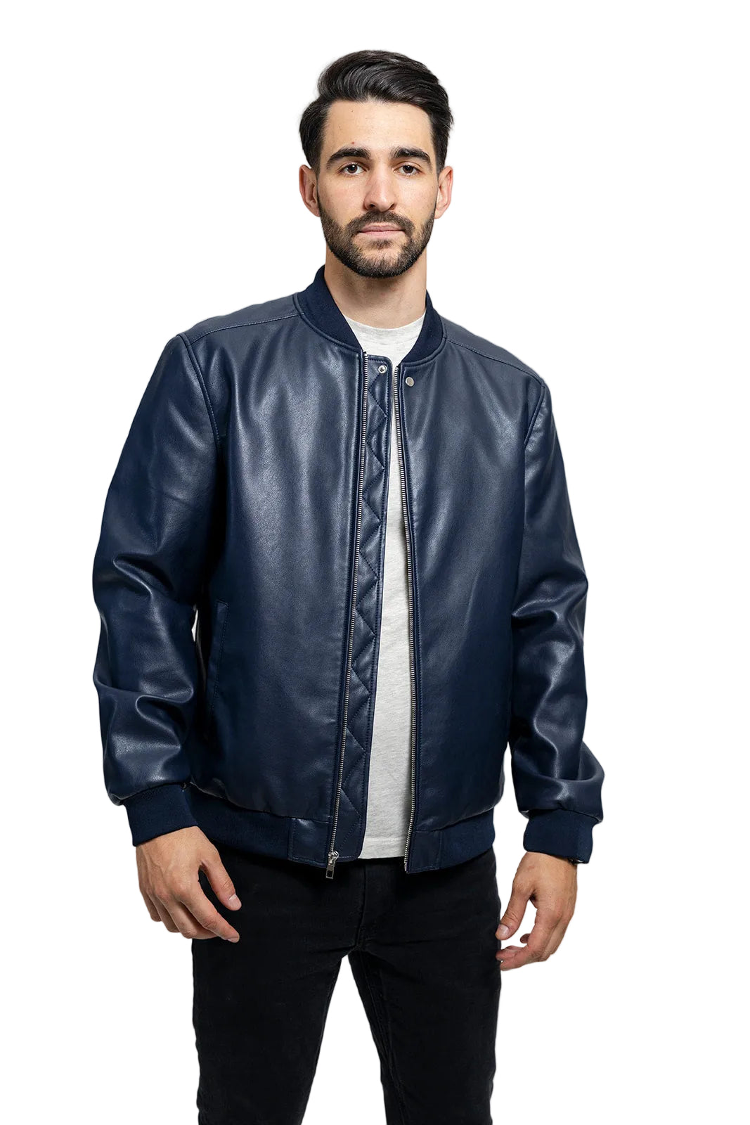 A man wearing a navy blue faux-leather bomber jacket over a white t-shirt and black pants, standing against a light gray studio background.