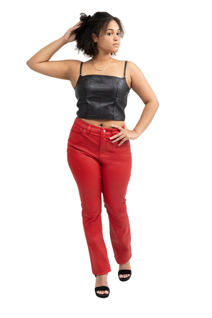 A woman modeling a black faux-leather spaghetti-strap crop top and bright red high-waisted pants against a white studio background.