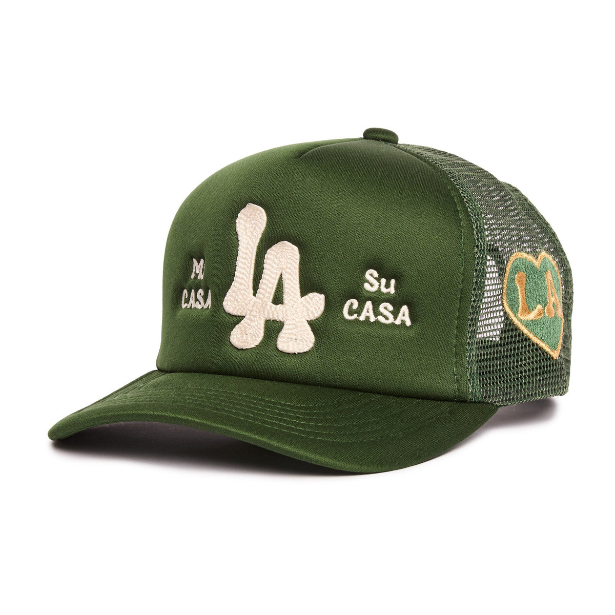 An olive green trucker hat with a curved brim, featuring a large beige embroidered 'LA' logo in the center, 'Mi CASA Su CASA' embroidered on the front panels, and a gold and green heart-shaped patch on the mesh back.