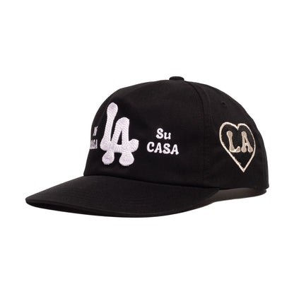 A black baseball cap featuring white embroidered 'LA' lettering, 'Su CASA' text, and a heart-shaped 'LA' patch on the side, set against a plain white background.