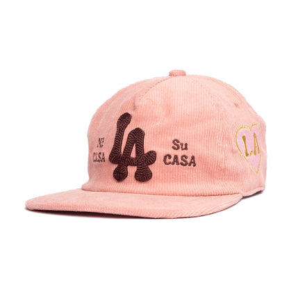 A light pink corduroy baseball cap with embroidered details. The front features a large dark brown embroidered '4' with '44' and 'Su CASA' text, and a gold and pink heart-shaped 'LA' on the side.
