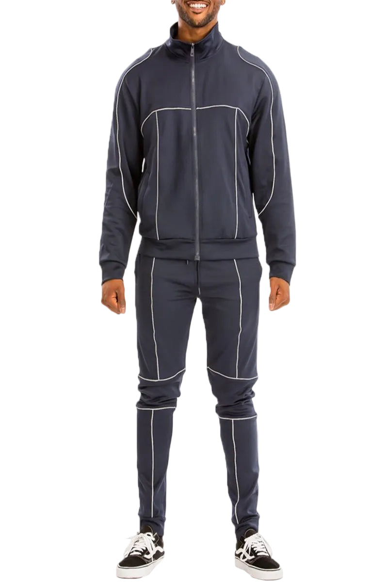 Man wearing a dark gray tracksuit with white piping on a white background