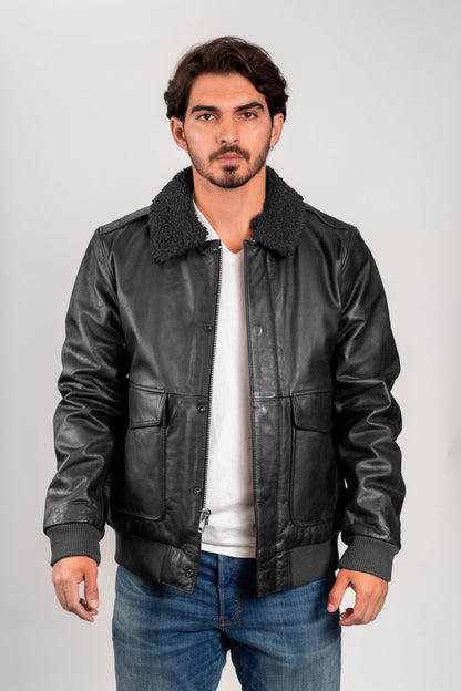 Man wearing a black leather jacket with a white shirt and blue jeans on a gray background