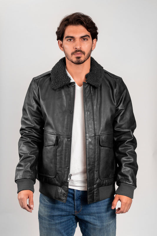 Man wearing a black leather jacket with a white shirt and blue jeans on a gray background