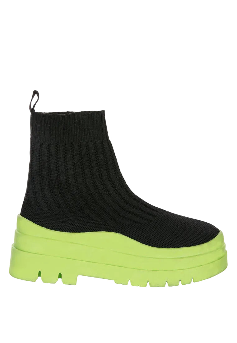 Black sock boot with a green platform sole on a white background