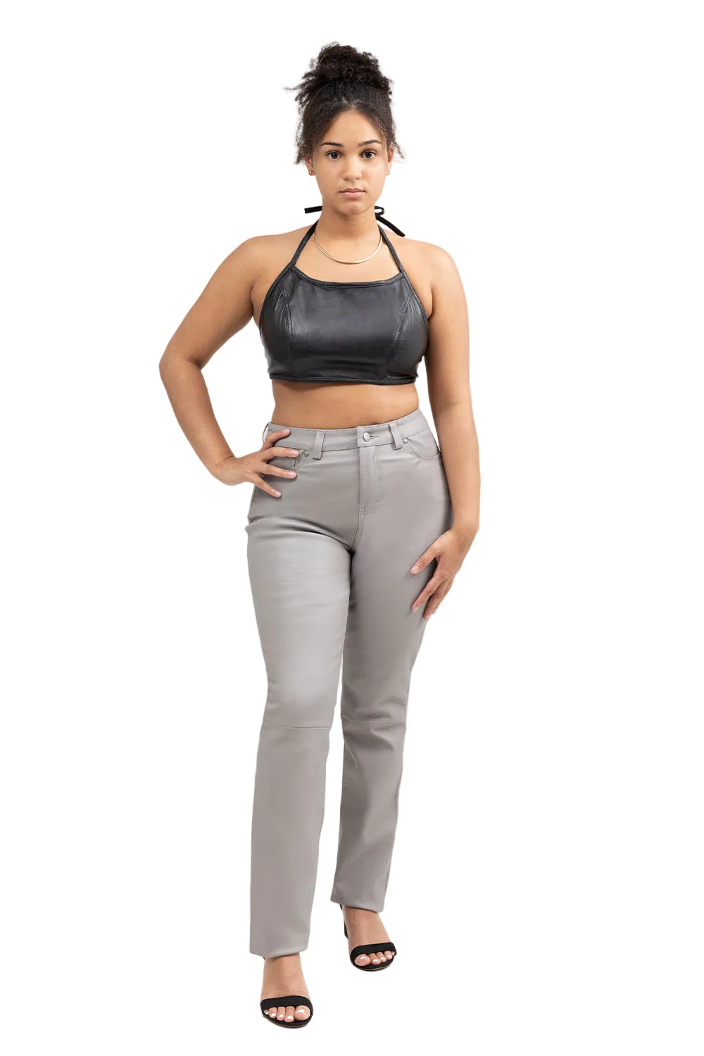 A woman modeling a black metallic halter crop top and light gray straight-leg jeans against a plain white studio background.