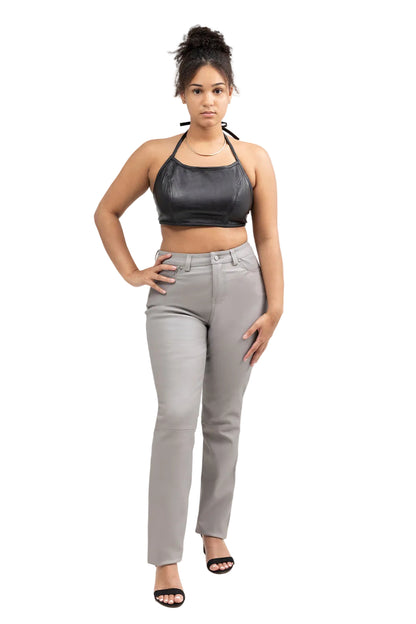 A woman modeling a black metallic halter crop top and light gray straight-leg jeans against a plain white studio background.